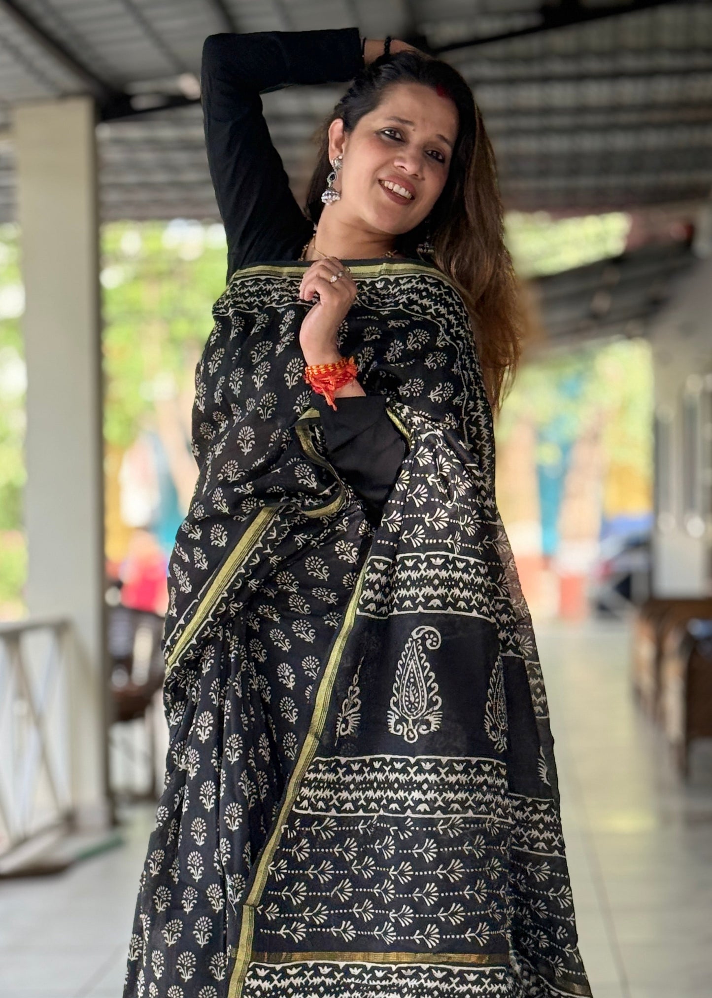 Woman wearing a black and gold traditional outfit with a patterned dupatta.