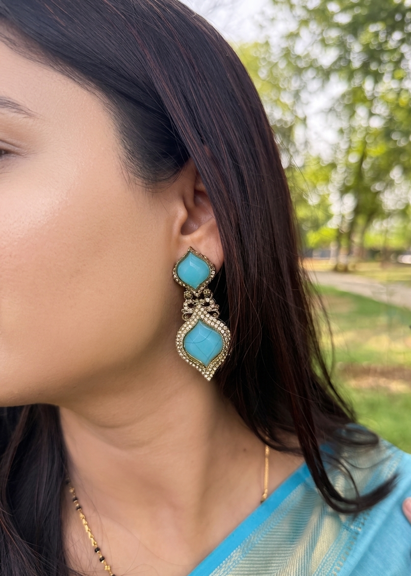 Woman wearing turquoise earrings with a blurred outdoor background