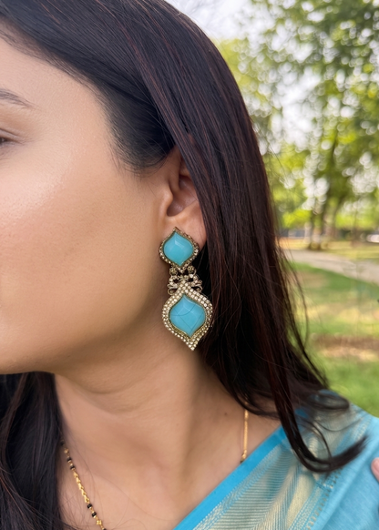 Woman wearing turquoise earrings with a blurred outdoor background