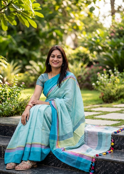 Woman in a blue saree sitting on steps with a garden background