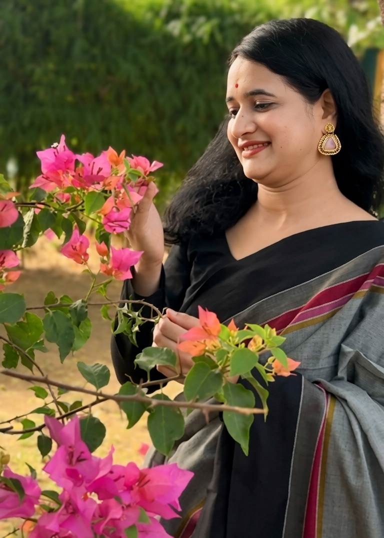 Woman in a black saree with a floral background