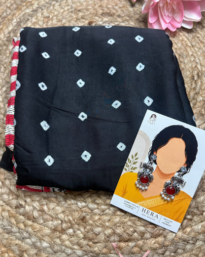 Black fabric with white patterns on a textured surface with pink flowers and a product card.