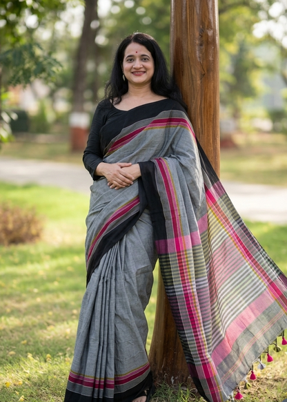 Woman in a gray saree with colorful patterns standing outdoors.