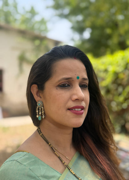 Woman wearing a green saree with a blurred outdoor background