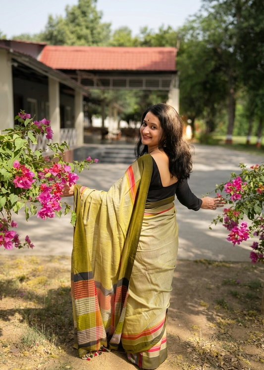 Woman in a saree standing outdoors with flowers and a building in the background