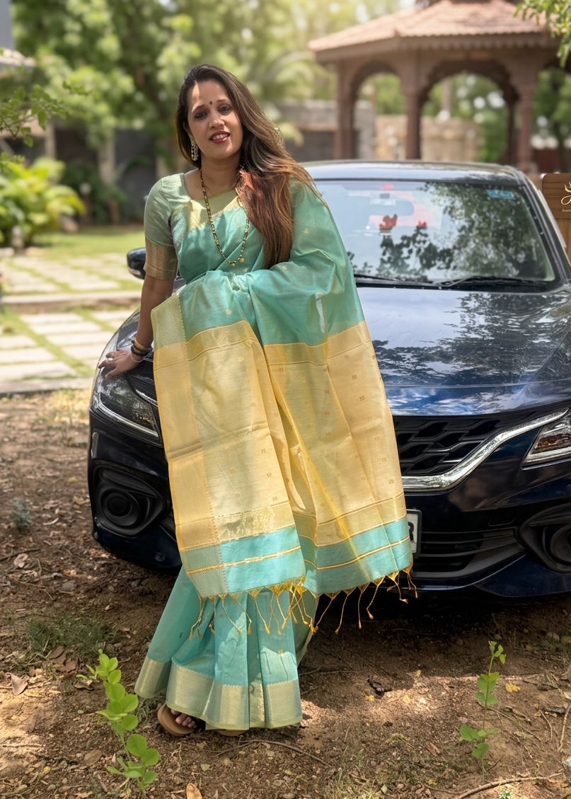 Woman in a teal saree standing next to a car outdoors