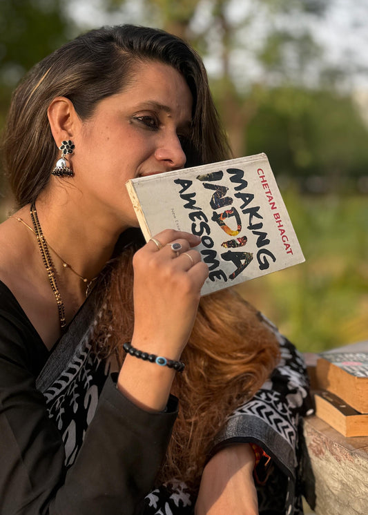 Woman holding a book titled 'Making India Awesome' with a blurred natural background